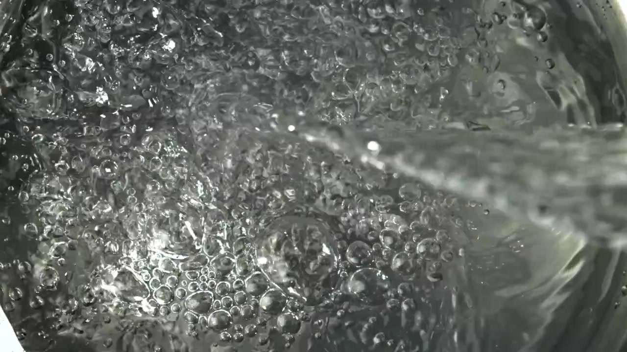 Primo piano di acqua limpida che si versa con bolle.