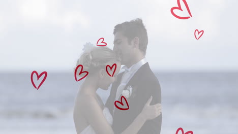 animation of red hearts over caucasian couple wearing wedding clothes and talking