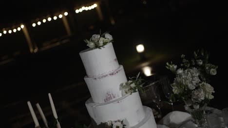 elegant white wedding cake adorned with delicate floral arrangements at night