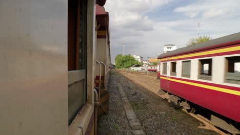 view of moving trains passing other trains on tracks at rail yard interchange, thailand