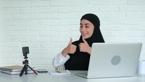 a beautiful woman of arab appearance blogger communicates with her subscribers via webcam. a muslim woman in a hijab is streaming and asking to subscribe and like the channel