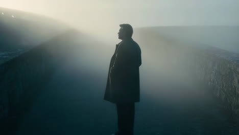 man in coat standing in fog