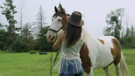 trained woman rider bonding with her male pinto horse, ruffling his mane