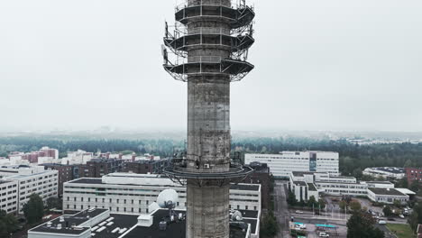 aerial medium shot of a bleak industrial concrete television and radio link tower in pasila, helsinki, finland on a bright and foggy day