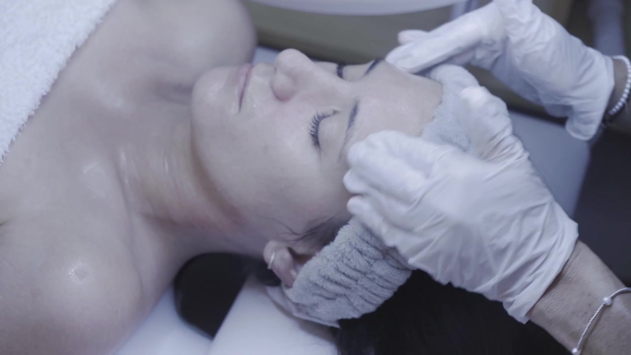 Dita guantate modellano delicatamente il viso in un massaggio facciale rilassante.