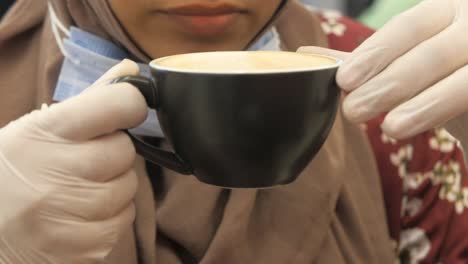 woman drinking coffee with gloves and mask