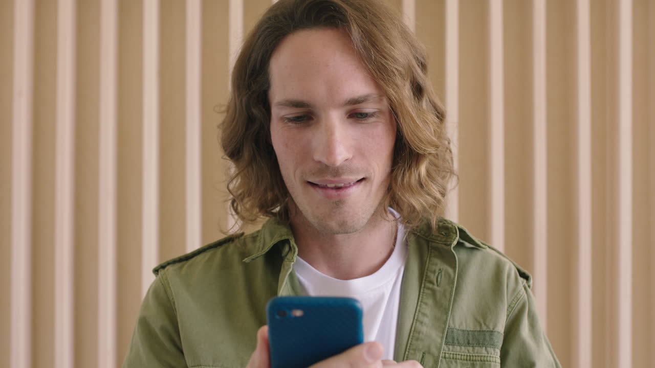 ritratto ravvicinato di un bel giovane uomo caucasico che invia messaggi di testo, naviga online utilizzando lo smartphone, utilizza la tecnologia mobile e gode della comunicazione digitale