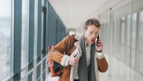 an angry young man walks down the hall and shouts on the phone