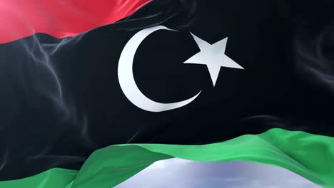 libya flag waving at wind with blue sky in slow, loop