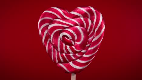 rotation of lollipop in heart shape on red background.candy on stick.saint valentine's day. the 14th of february.women's day.love concept.macro.