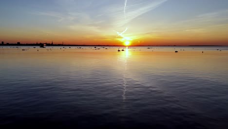 un avión no tripulado vuela sobre el mar báltico durante la puesta del sol con el horizonte de tallin, la capital de estonia, en el fondo.