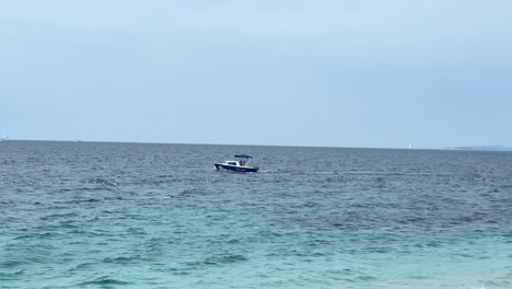 a small motorboat drifts on the open sea with a soft ripple on the water. overcast sky creates a peaceful maritime atmosphere with distant horizon