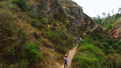 group of hikers trekking along a narrow historical trail near inkilltambo, cusco, peru