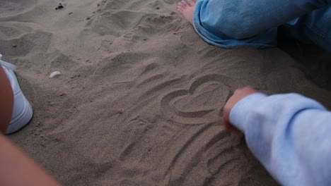 Eine-Person-Zeichnet-Mit-Dem-Finger-Ein-Herz-In-Den-Sand