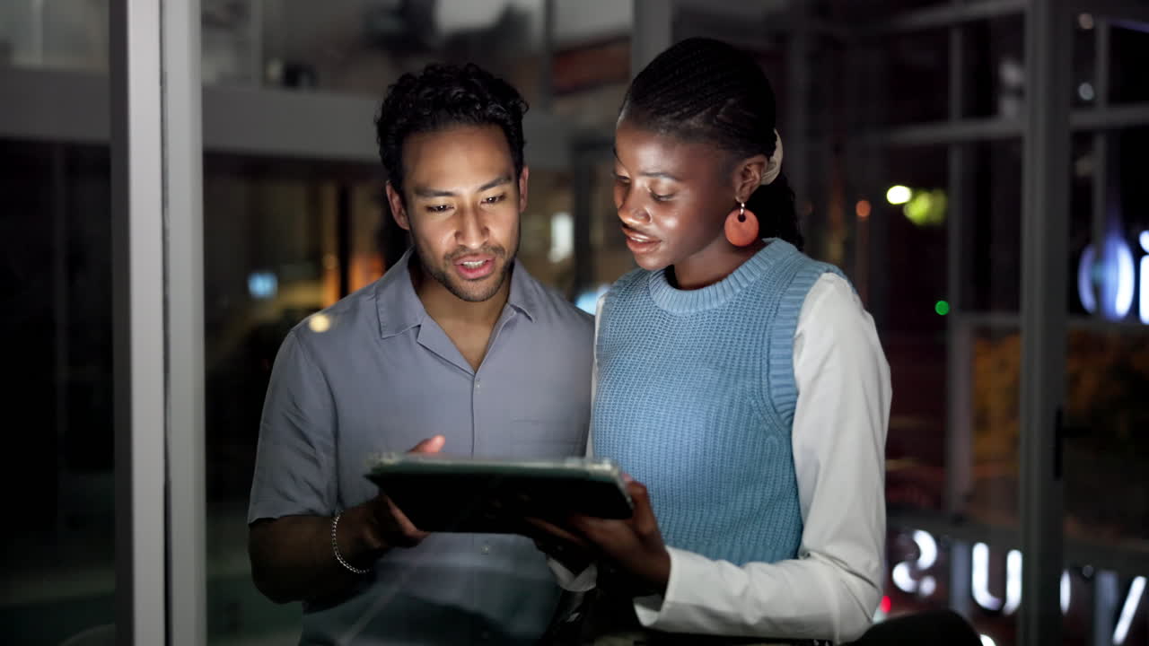 Diverse Colleagues Discussing Project on Digital Tablet in Office at Night