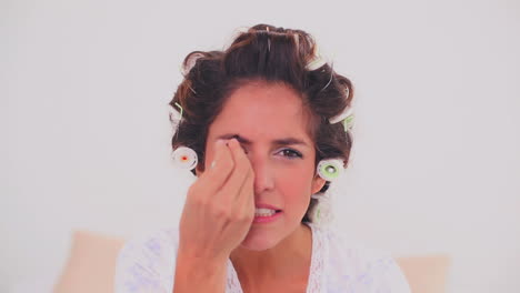 mujer concentrada en rizos de cabello arrancándose la ceja