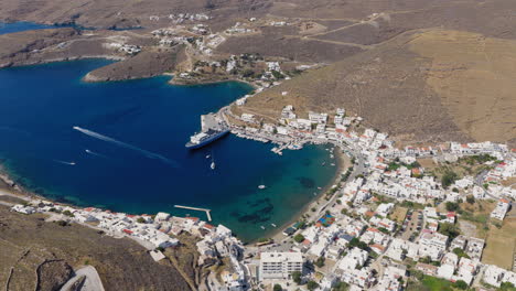 merichas port and gialos beach seen from above, with whitewashed buildings and calm blue waters reflecting the summer sun