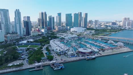 aerial establishing shot of miami city skyline with ferris wheel at harbor port during sunset time, usa