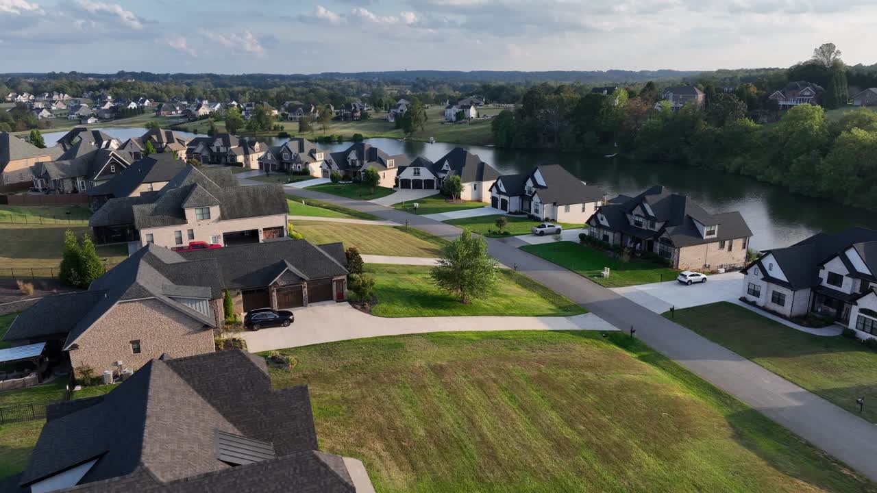 Moderno quartiere suburbano americano con case di lusso, prati verdi, ampi vialetti e un lago sullo sfondo. Vista aerea. Zona residenziale tranquilla ed esclusiva in Virginia, USA