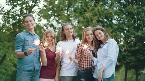 happy friends with sparklers having fun outdoors