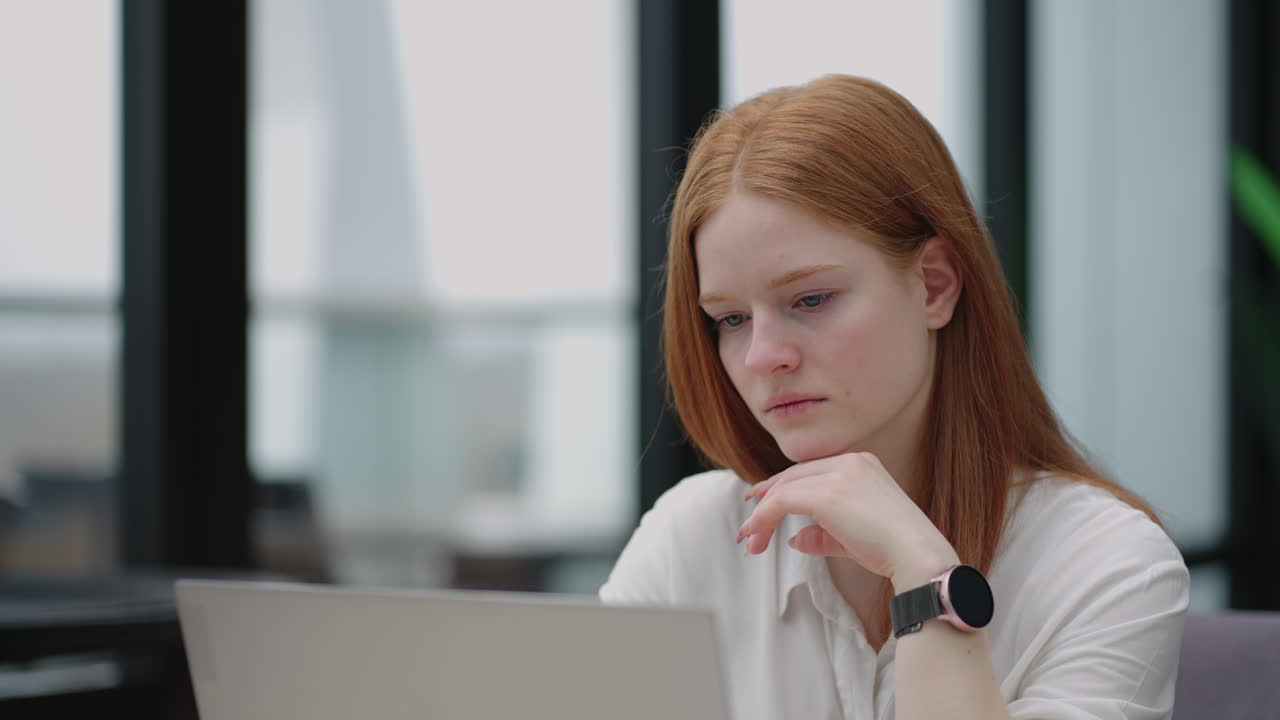Thoughtful concerned redheaded woman working on laptop computer looking away thinking solving problem at office serious woman search for inspiration make decision feel lack of ideas