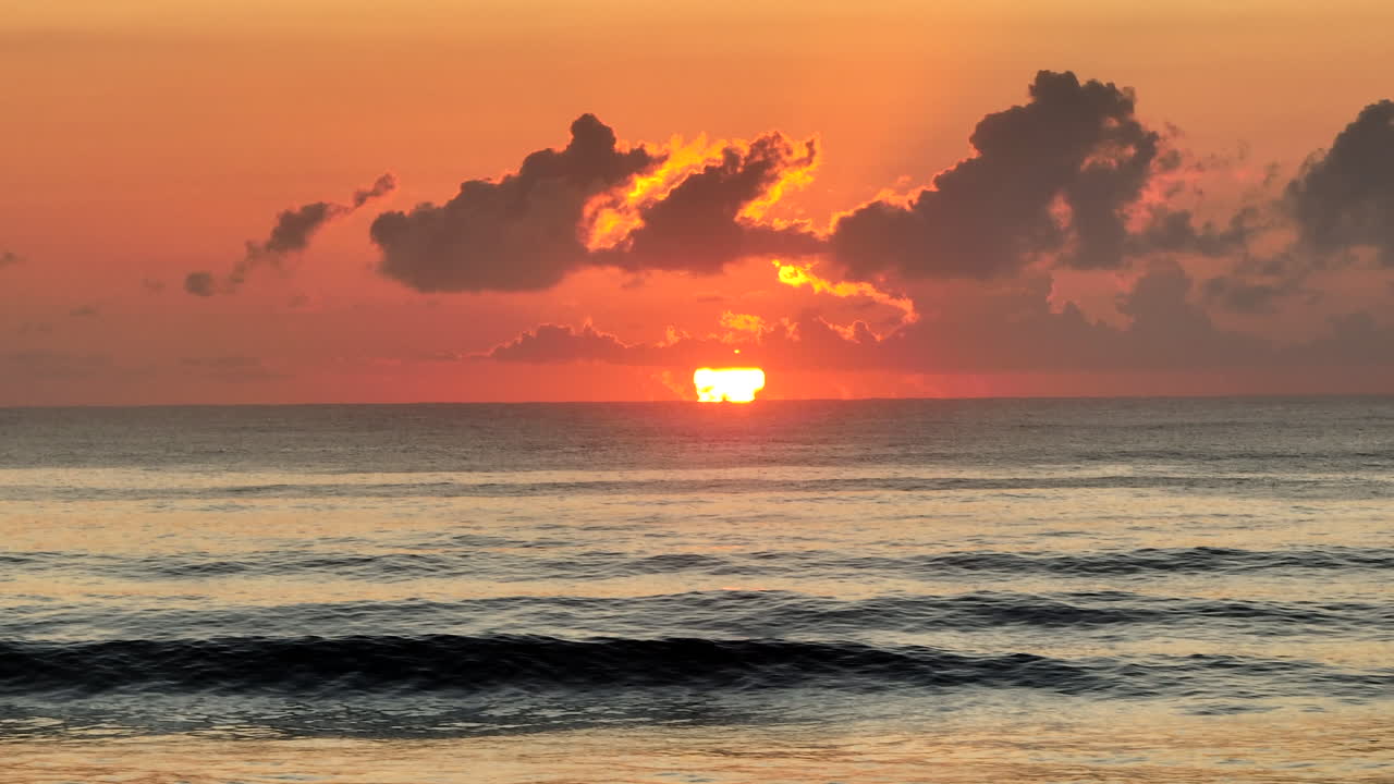 横向きのドローンによるオーストラリアの静かな海の波の上のカラフルな日の出の空中撮影