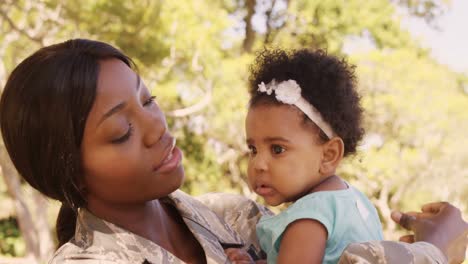 soldier mother holding her daughter in a park