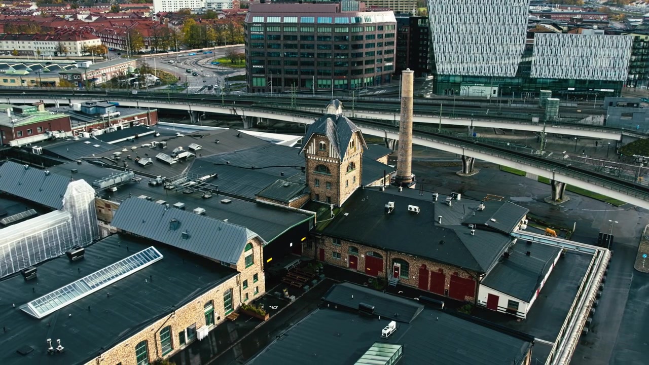 Etablerande drönarbild från luften av de historiska Slakthuset-byggnaderna, omgivna av järnvägsspår och stadsinfrastruktur i Göteborg, Sverige.
