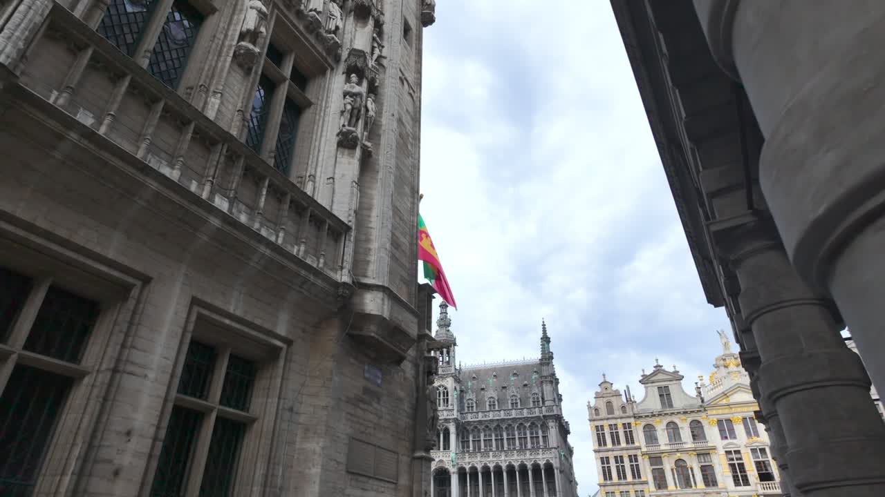 Low angle view of Grand Place in Brussels, Belgium, showing a waving brussels flag in a cloudy day. push forward