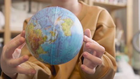 close up view of unrecognizable kid playing with a globe in a craft workshop