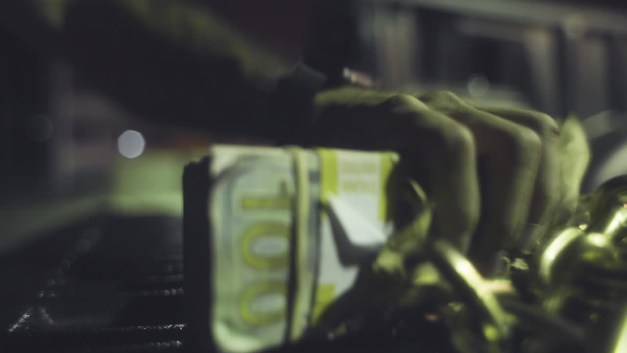 un ladrón roba una bolsa de dinero de la parte trasera de un camión por la noche