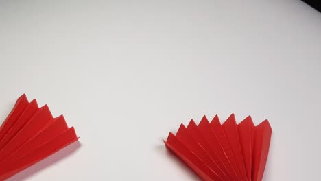 colored origami paper looks like a red fan on a white background. chinese new year holiday background, creativity, top view, 4k video