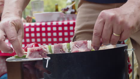 close-up of an unrecognizable man flipping skewer of kebab on grill