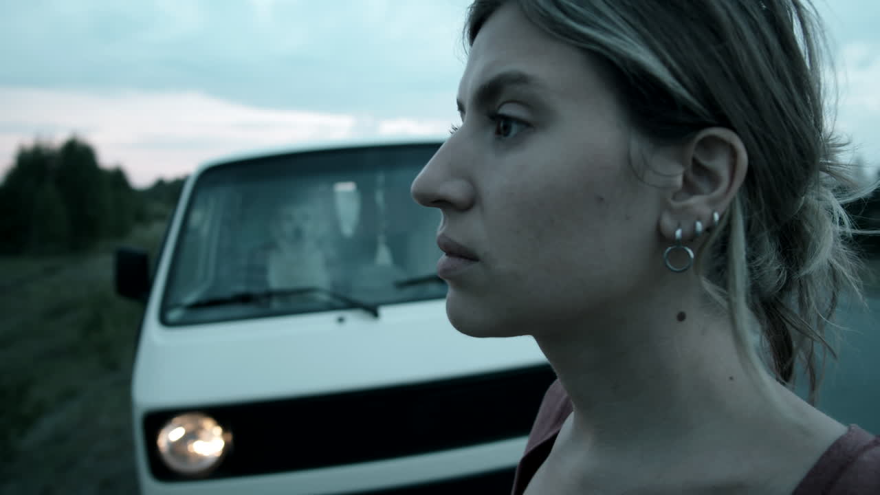 밴 근처에 서서 자연을 바라보는 여자