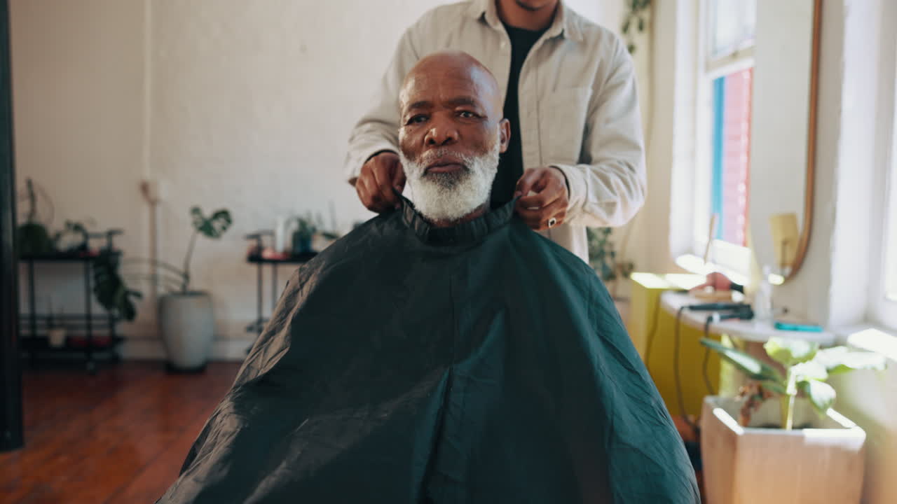 Barber sætter kappe på ældre mand i moderne barbershop.