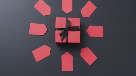 Video-of-gift-tags-with-red-gift-box-with-ribbon-and-copy-space-on-black-background