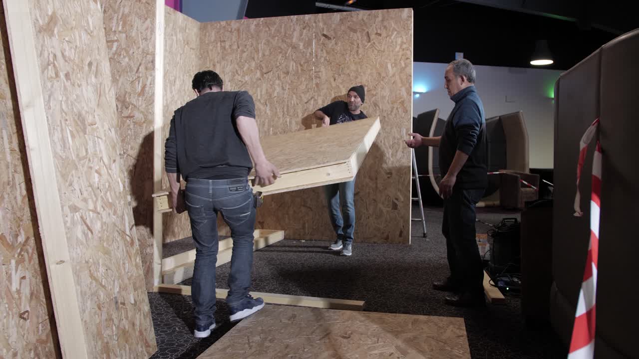 Construction Workers Assembling Plywood Panels Indoors