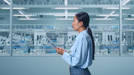 vista lateral de una trabajadora profesional asiática de pie en la digitalización de la fábrica para un proyecto innovador, observa mirando hacia arriba luego llega a concentrarse en el teléfono y seguir comprobando