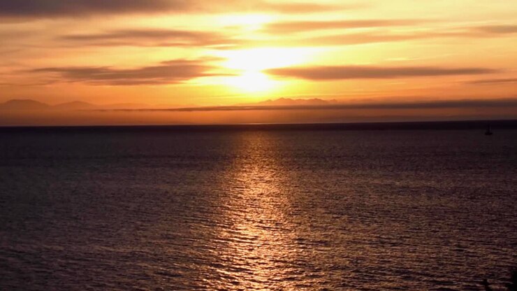 Bright orange sunset over reflective rippling lake in Texas, long shot