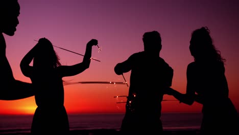 Young-adult-friends-having-fun-on-the-beach-at-night-with-sparklers-4k