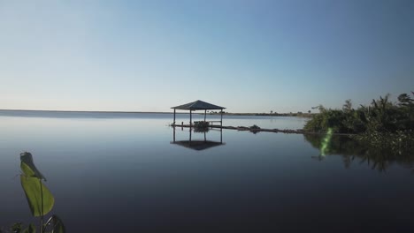 Gimbal-slomo-shot-of-wooden-gazebo-on-river-during-daytime