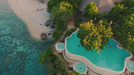 revealing-zoom-in-aerial-shot-of-a-private-infinity-pool-on-top-of-a-cliff-that-opens-up-to-a-blue-green-ocean-for-surfing-or-maritime-explorers