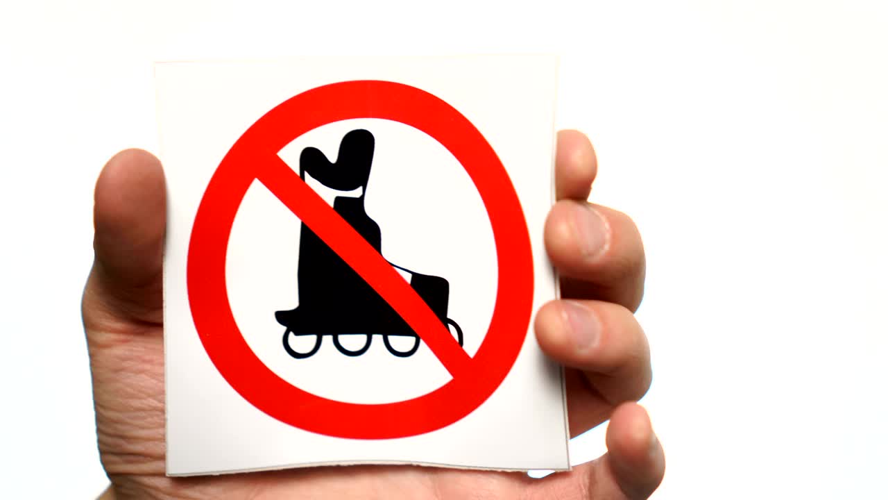 No roller skating allowed sign isolated. Male hand holding no roller skating sign