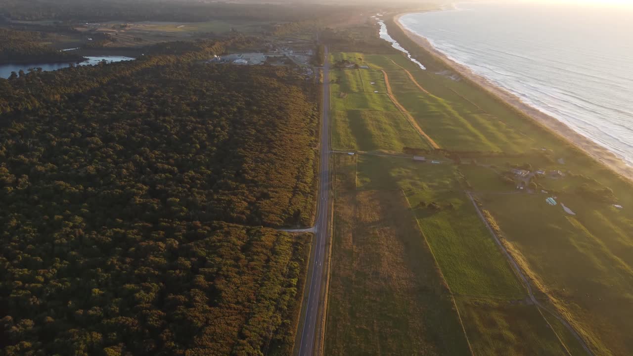 vista de avión no tripulado de la costa, los bosques y un camino junto al mar durante la puesta de sol en hokitika, costa oeste, nueva zelanda