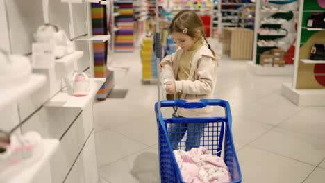 niña pequeña en una tienda de zapatos con carrito de compras