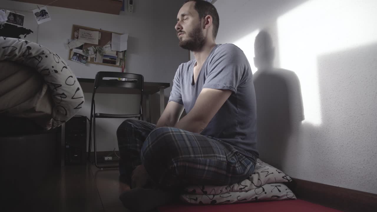 Man meditating in the early morning, sun shining, low angle shot
