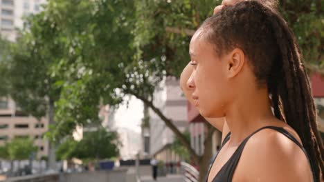 Side-view-of-young-African-American-woman-standing-on-a-bridge-in-the-city-4k