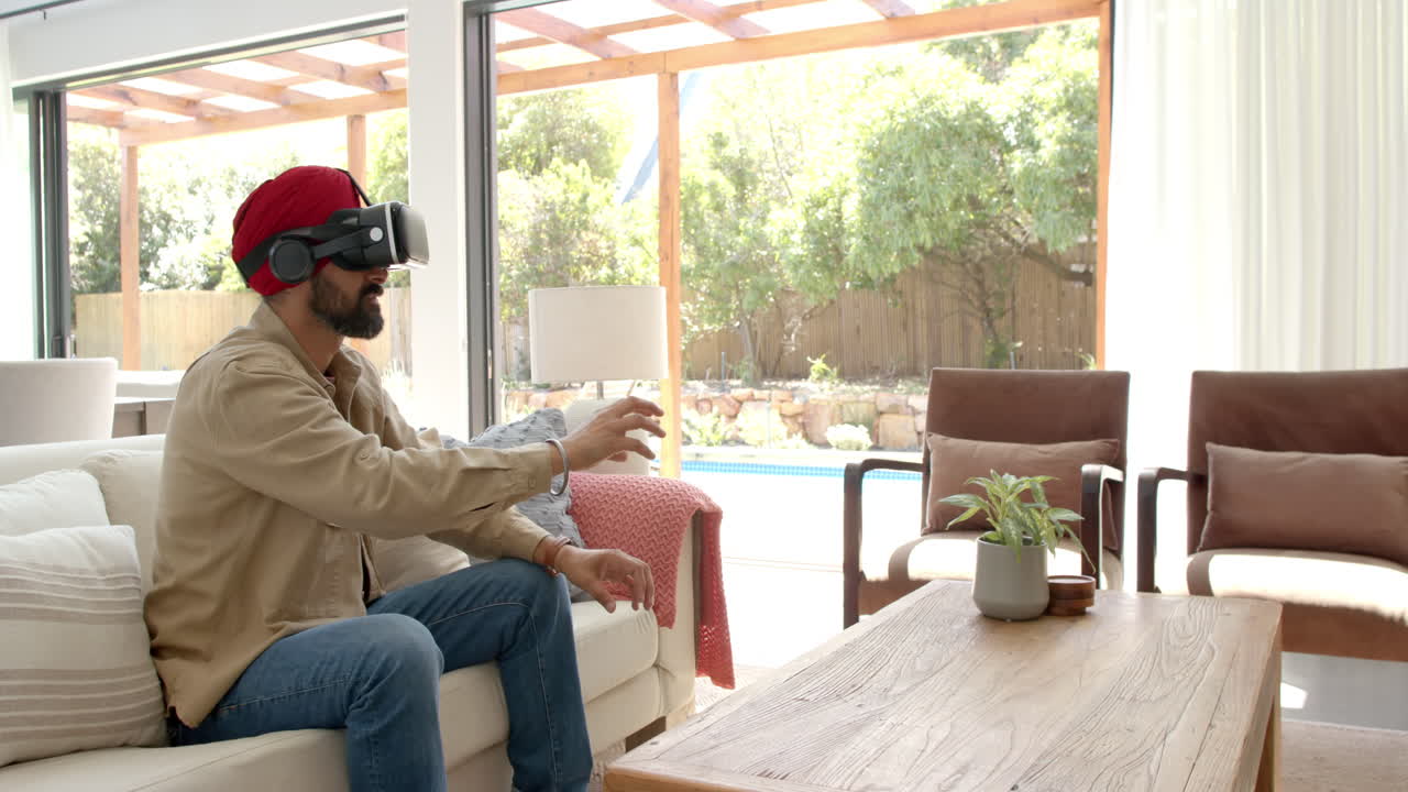 Using VR headset, man sitting on sofa and interacting with virtual environment
