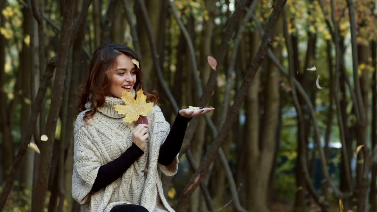 Fashion woman walking in autumn park. Outdoor fashion video of young beautiful lady surrounded autumn leaves