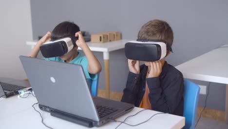 two classmates putting on vr glasses at desk